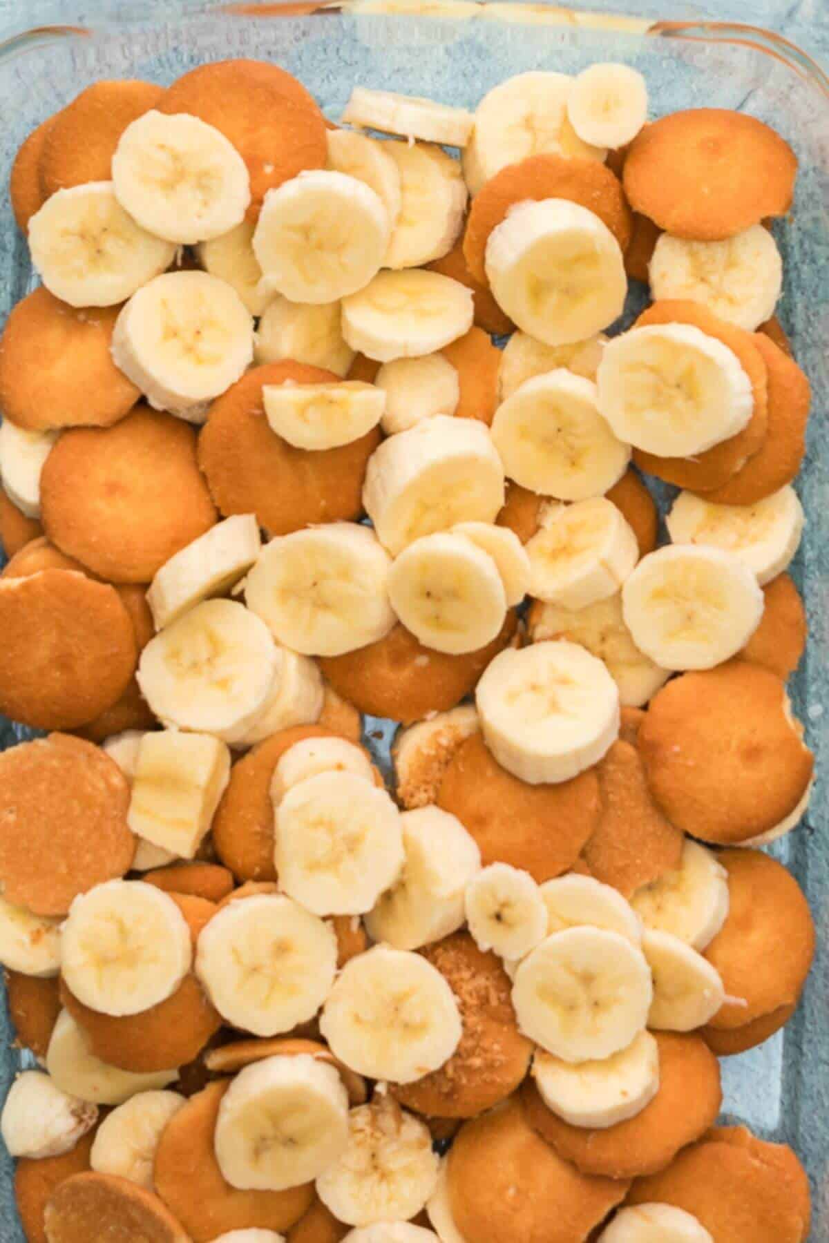 A dish filled with sliced bananas and round vanilla wafers arranged in layers.