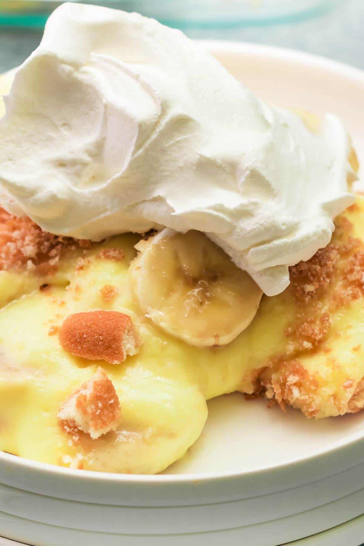 Close-up of a plate with banana pudding topped with crumbled cookies and a dollop of whipped cream.
