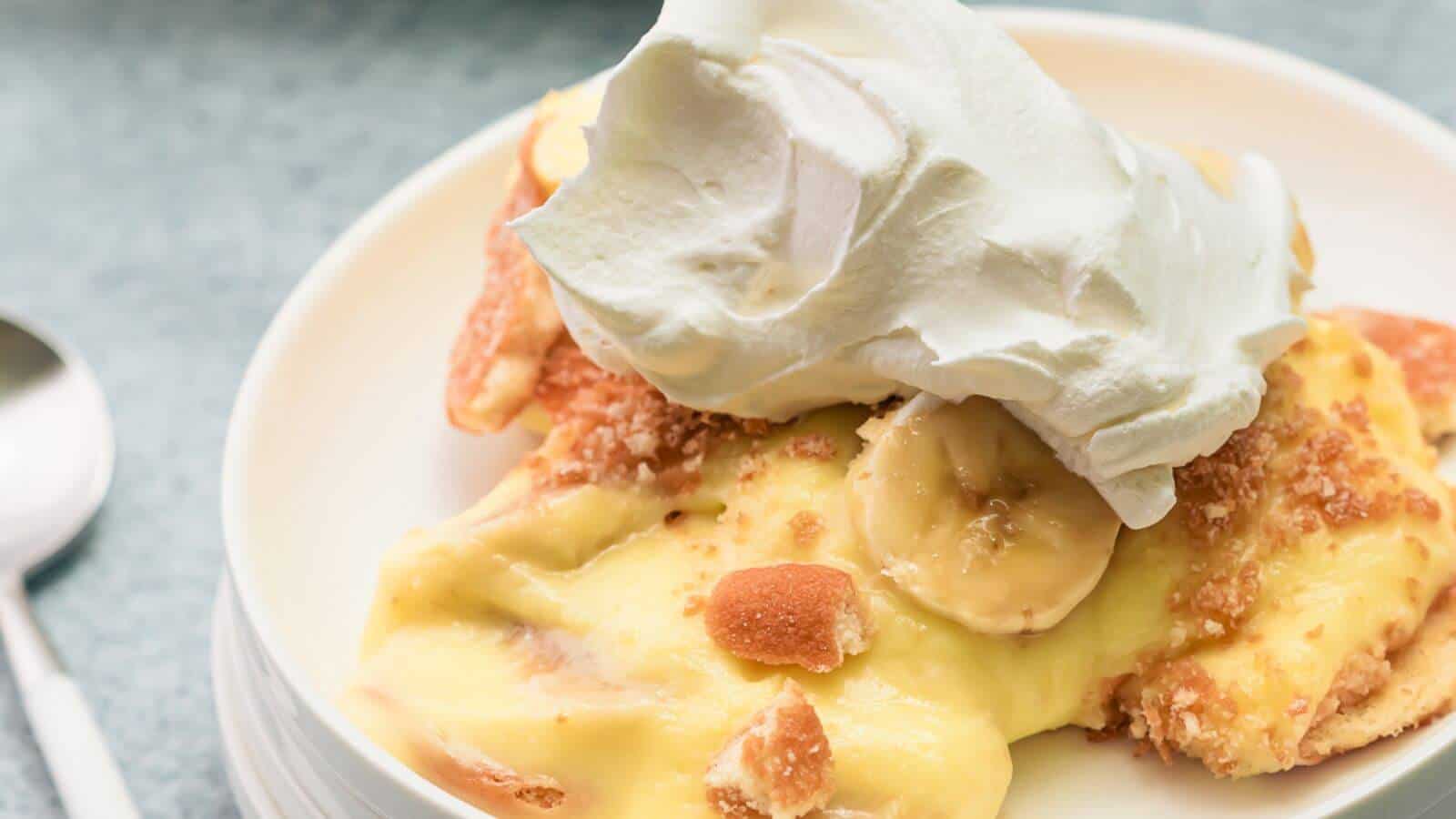 Slice of banana pudding topped with whipped cream on a white plate.