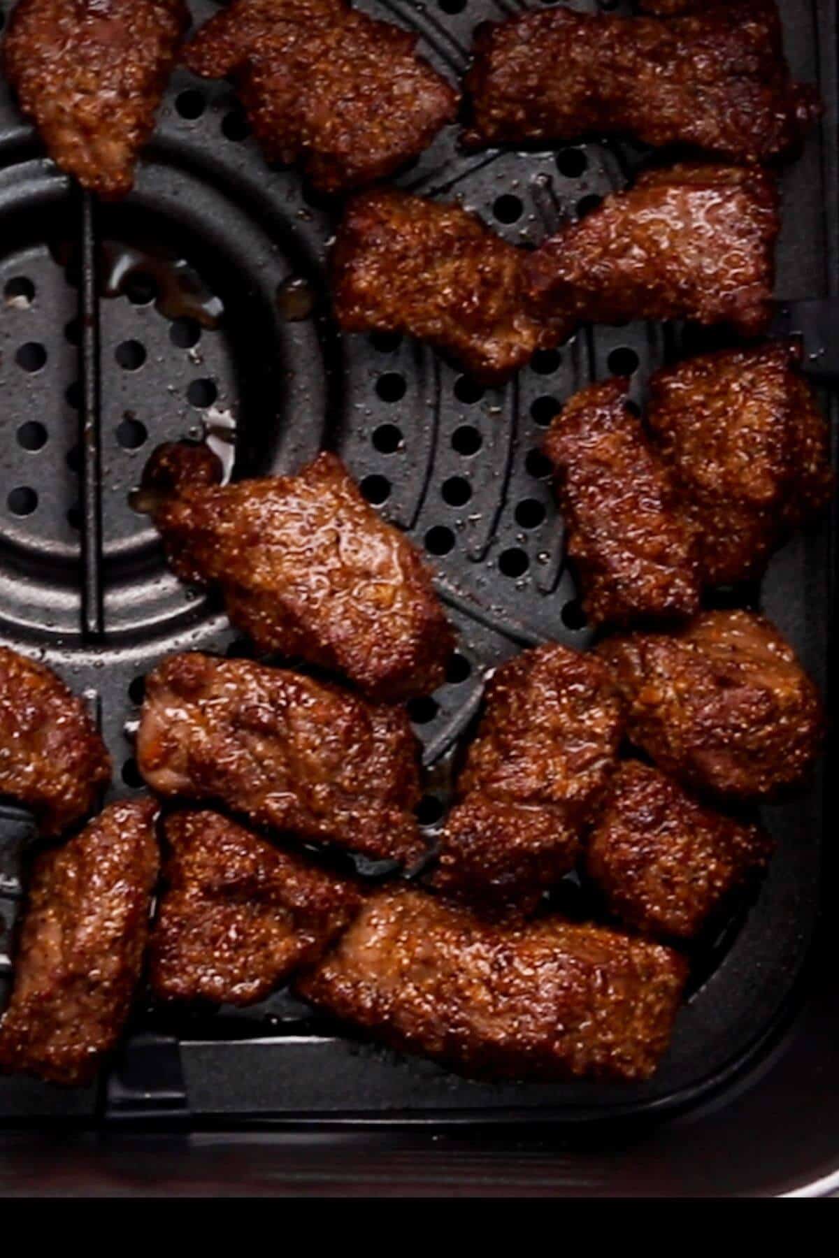 Cooked meat pieces arranged on a black grill tray.