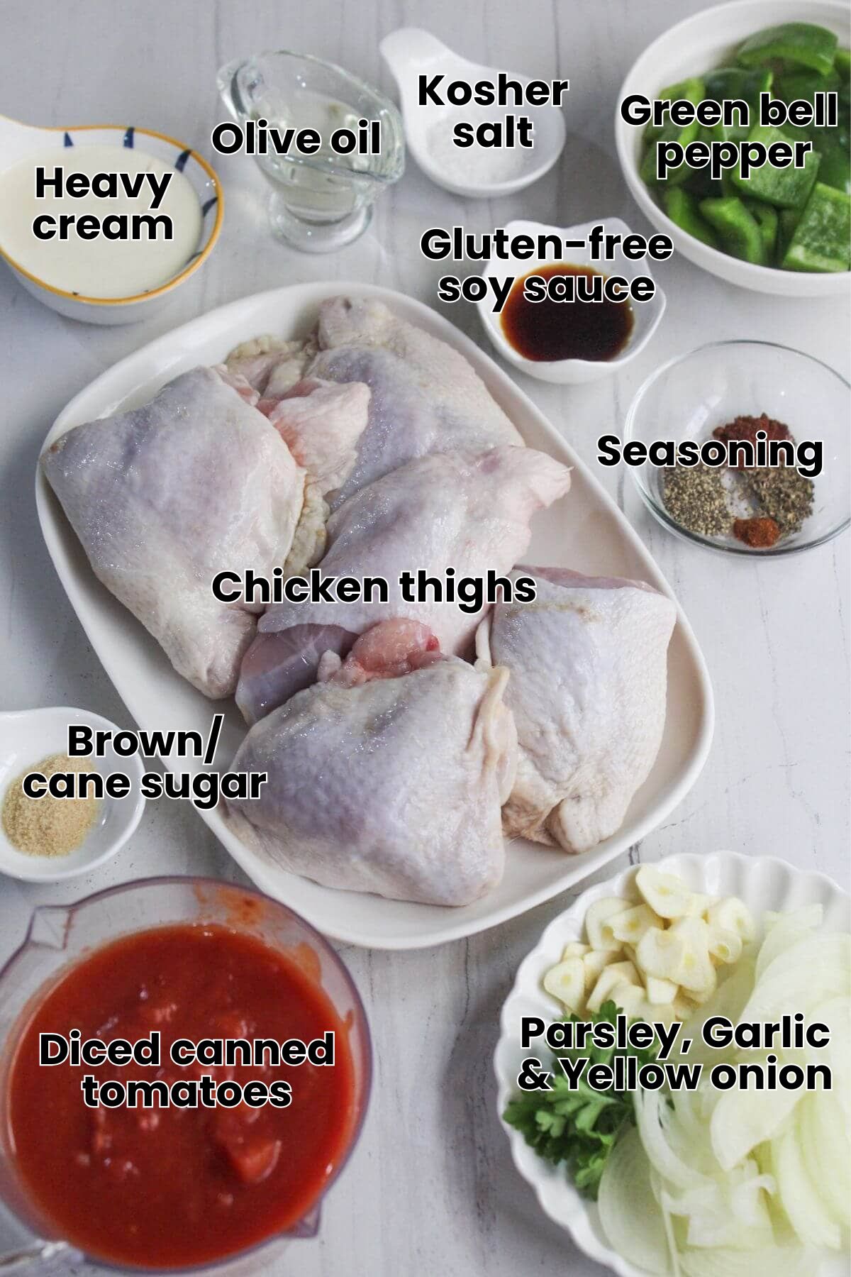 Ingredients on a marble surface: chicken breasts, tomato sauce, mozzarella cheese, ham slices, garlic, parsley, cream, salt, and pepper in separate bowls.