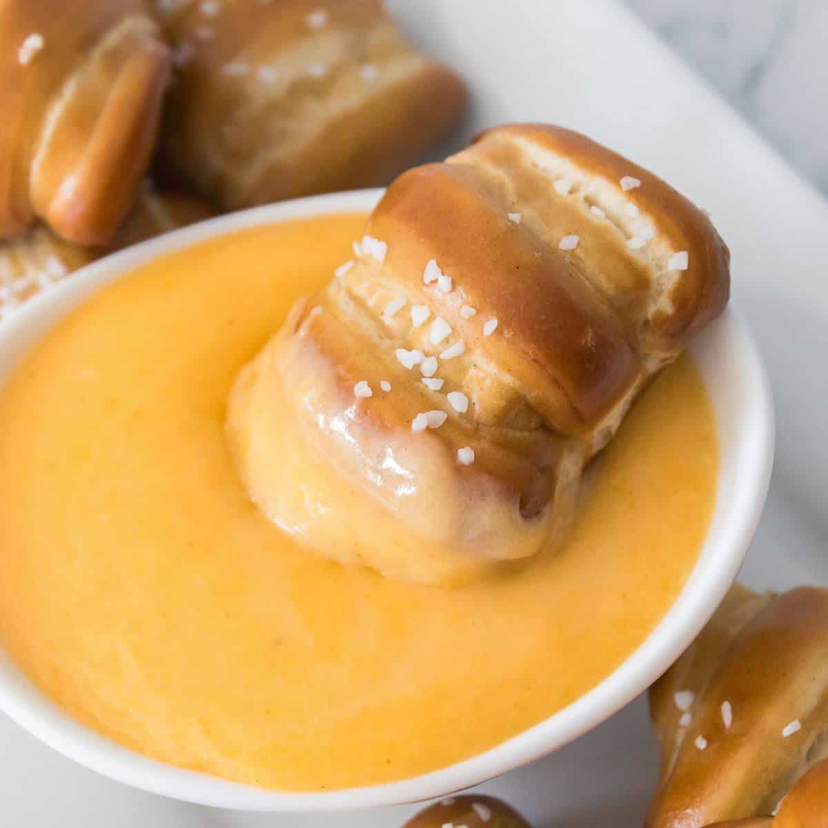Soft pretzel dipped in a bowl of creamy cheese sauce.