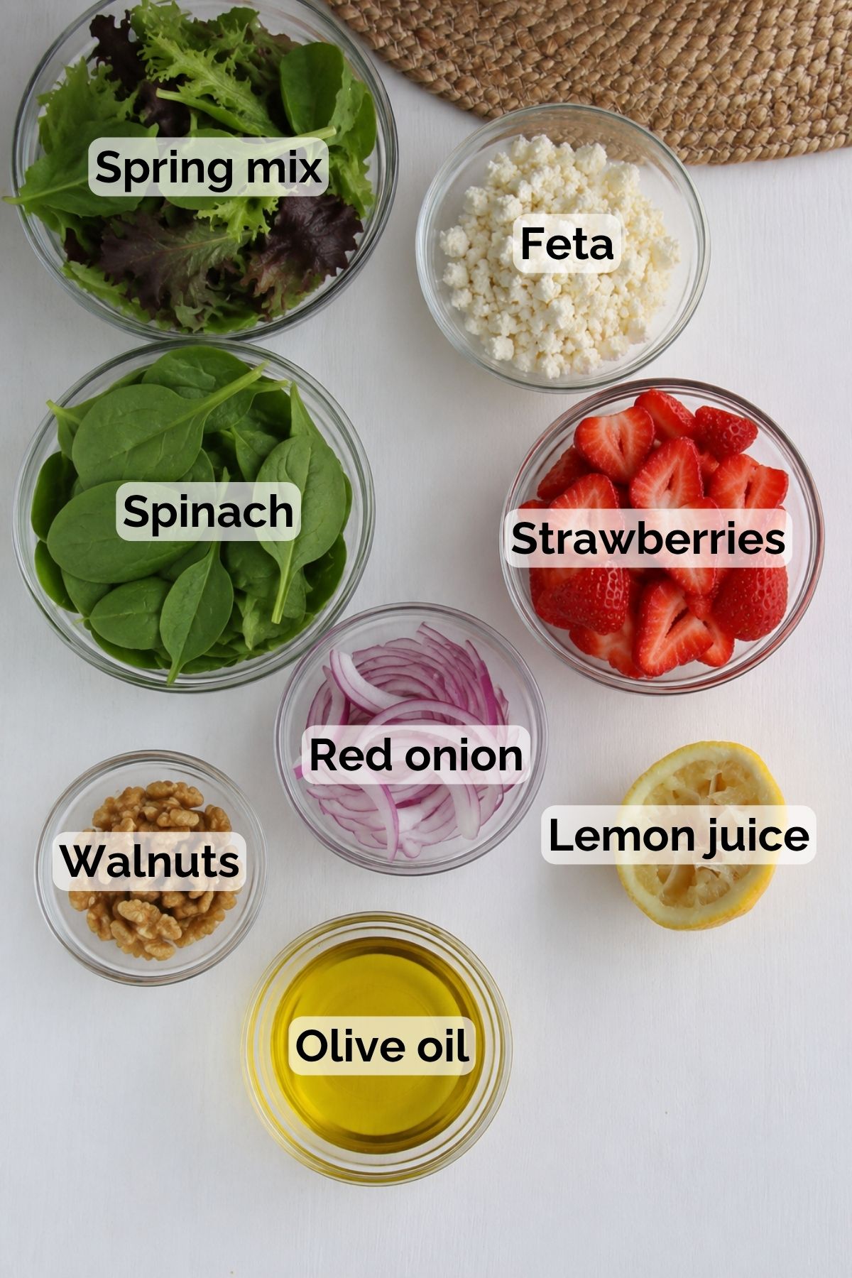 Ingredients for a strawberry spinach salad with text over the ingredients.