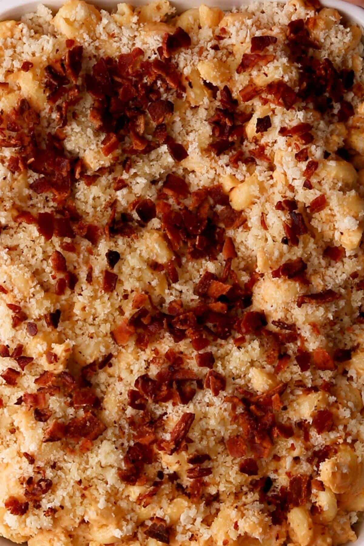 A close-up of baked mac and cheese topped with breadcrumbs and crispy bacon bits.