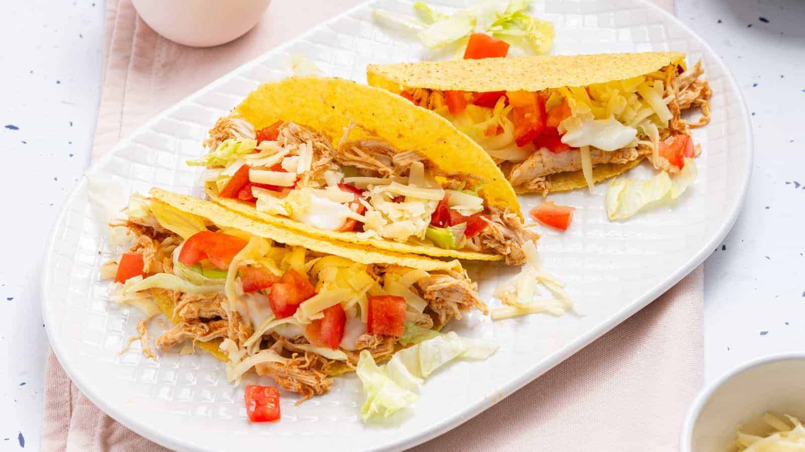 Two tacos on a plate with a bowl of guacamole.