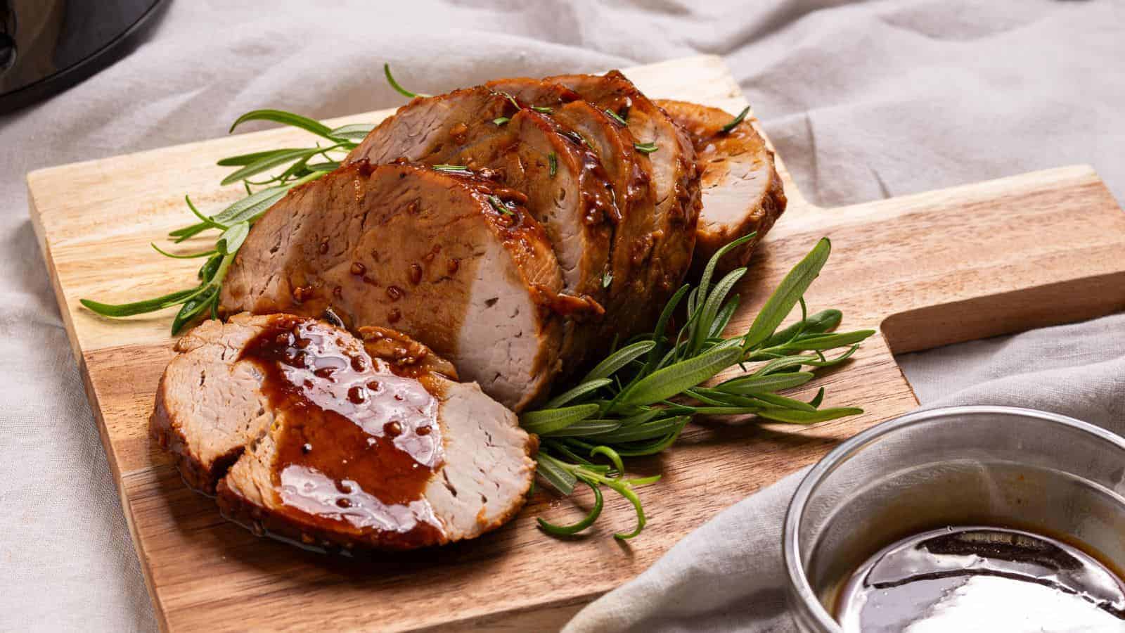Pork tenderloin on a cutting board next to a slow cooker.