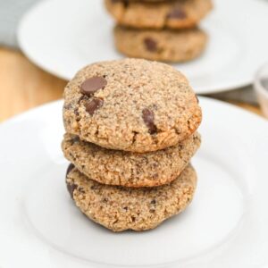 Three stacked chocolate chip cookies on a white plate.