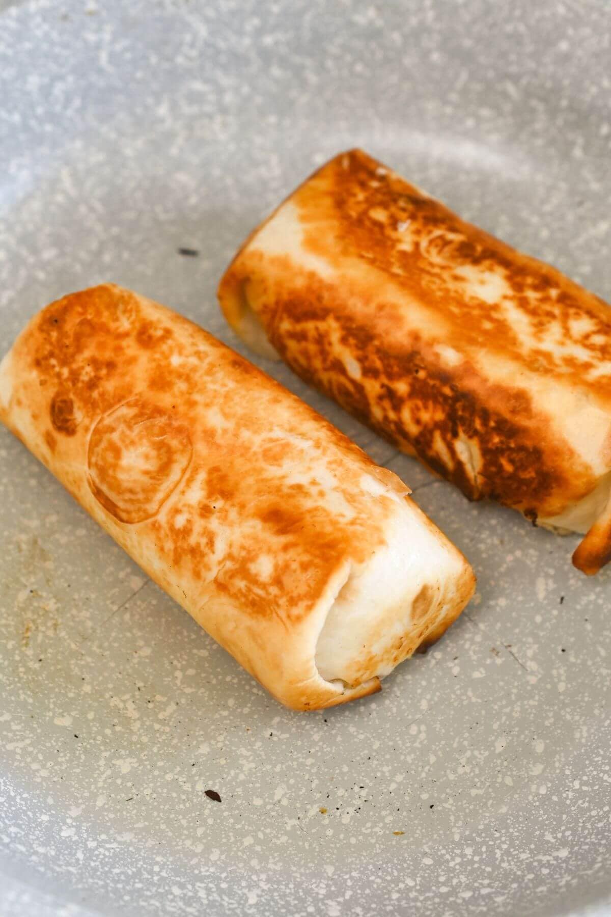 Two golden-brown, pan-fried rolls in a skillet.