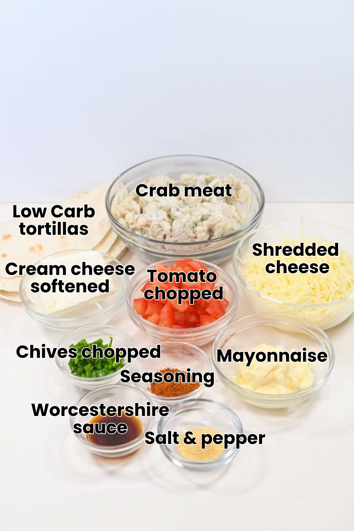 Ingredients arranged on a table include chopped chicken, diced tomatoes, shredded cheese, tortillas, cream cheese, spices, mayonnaise, soy sauce, and chopped green onions in clear bowls.