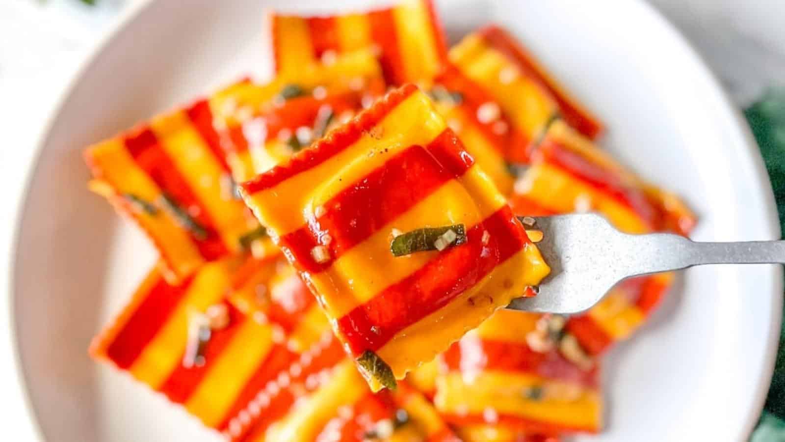 Closeup of a red and yellow lobster ravioli on a fork.
