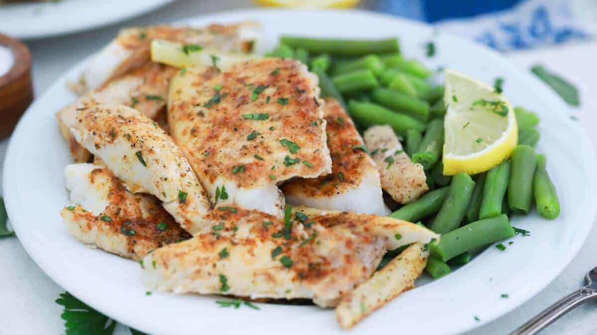 Baked lemon butter fish fillet seasoned with herbs and spices, garnished with lemon slices and chopped parsley,.