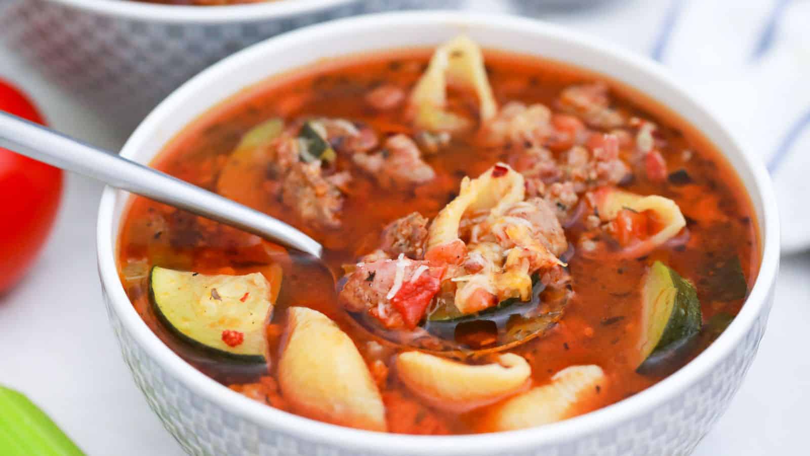Minestrone Soup with Sausage in white bowl with spoonful.