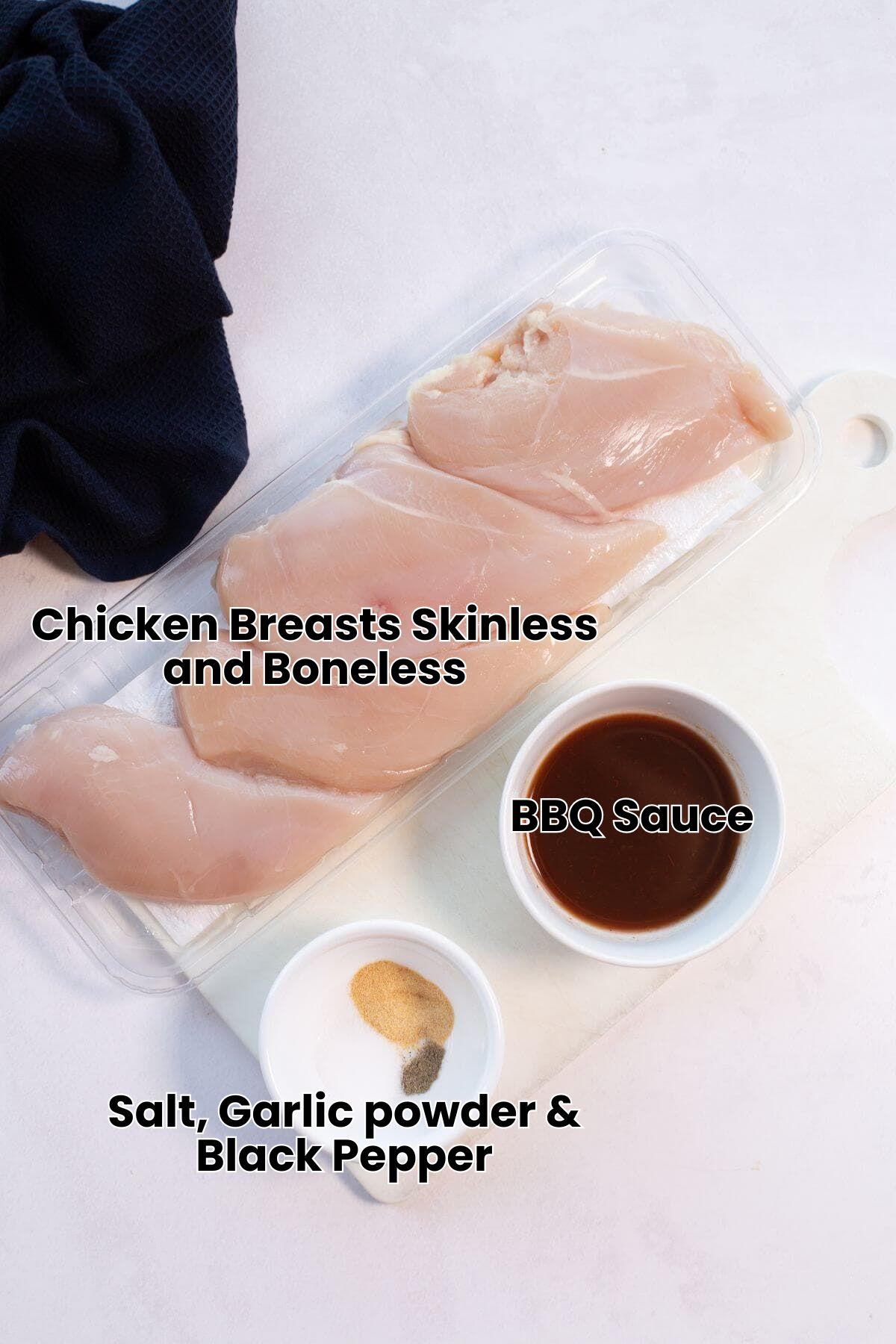 Four raw chicken breasts on a tray beside small bowls of sauce and seasoning on a white cutting board.