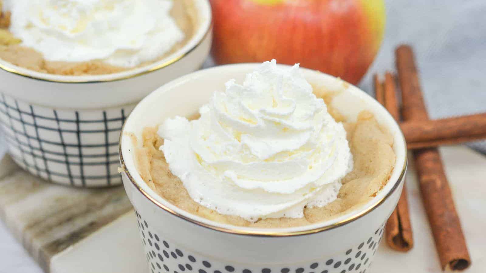 Apple mug cakes in ramekins with cinnamon sticks.