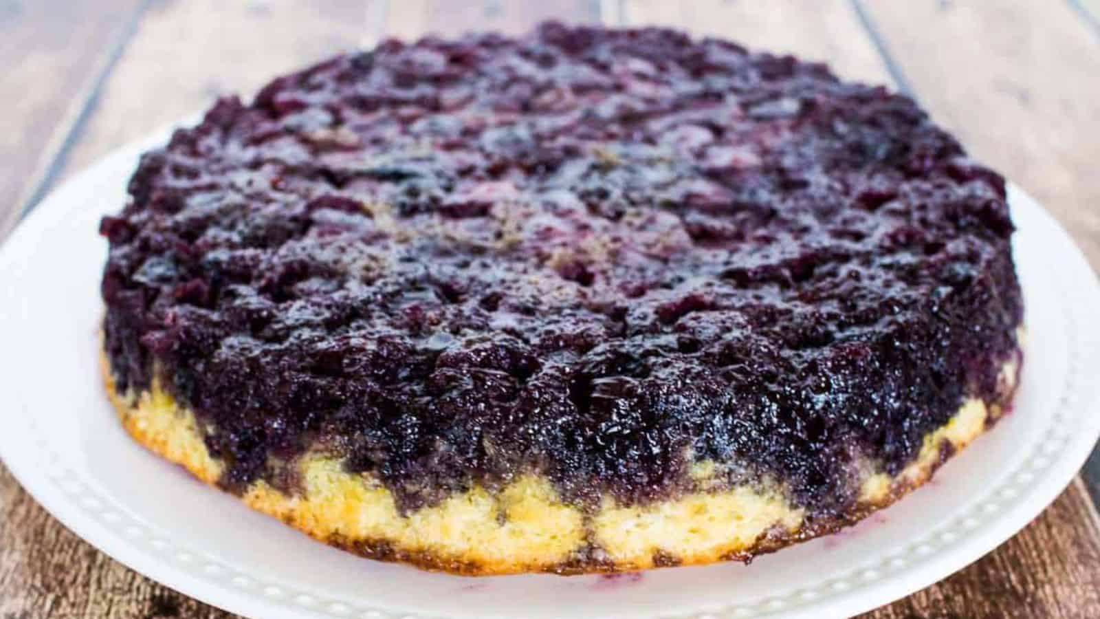 Blueberry upside down cake on a white plate before slicing.