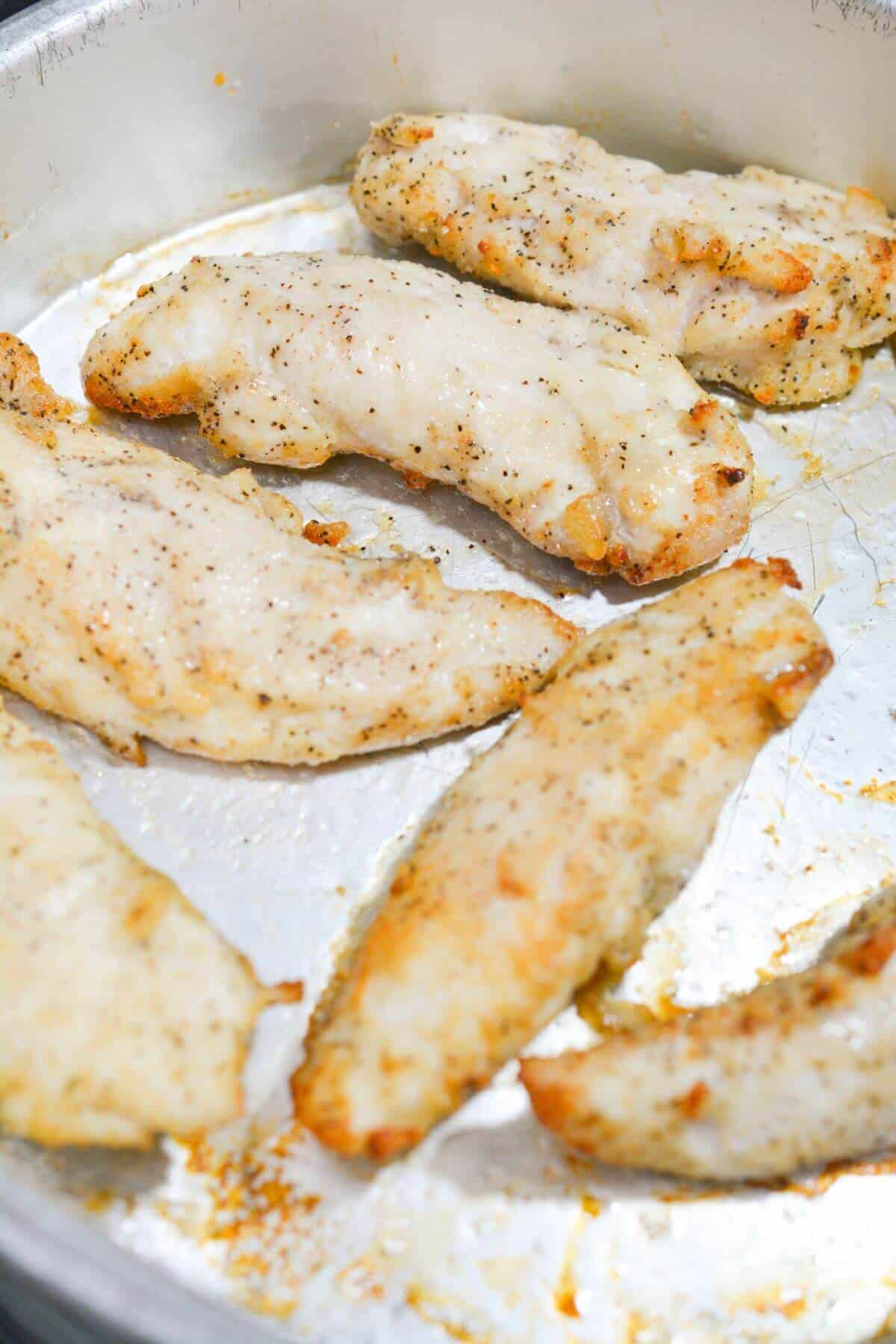 Pan with seasoned and cooked chicken strips.