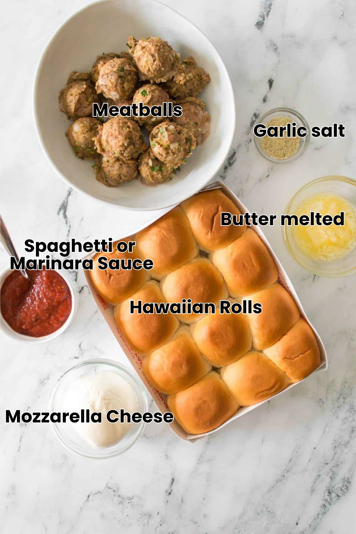 A tray of twelve slider buns, a bowl of cooked meatballs, a bowl of marinara sauce, shredded cheese, melted butter, and breadcrumbs on a marble surface.