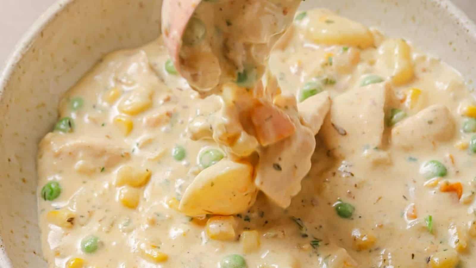 Chicken pot pie soup in a white bowl with a spoon.