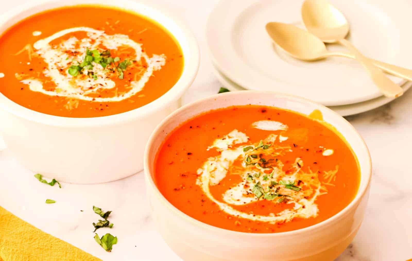 Two bowls of soup with sour cream on top.