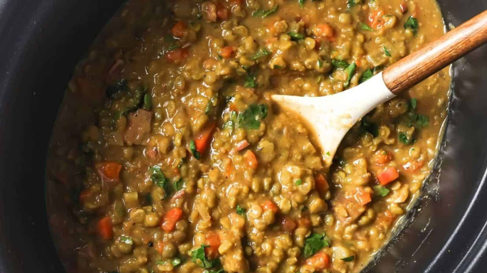 Slow cooker split pea soup in a slow cooker with a spoon.