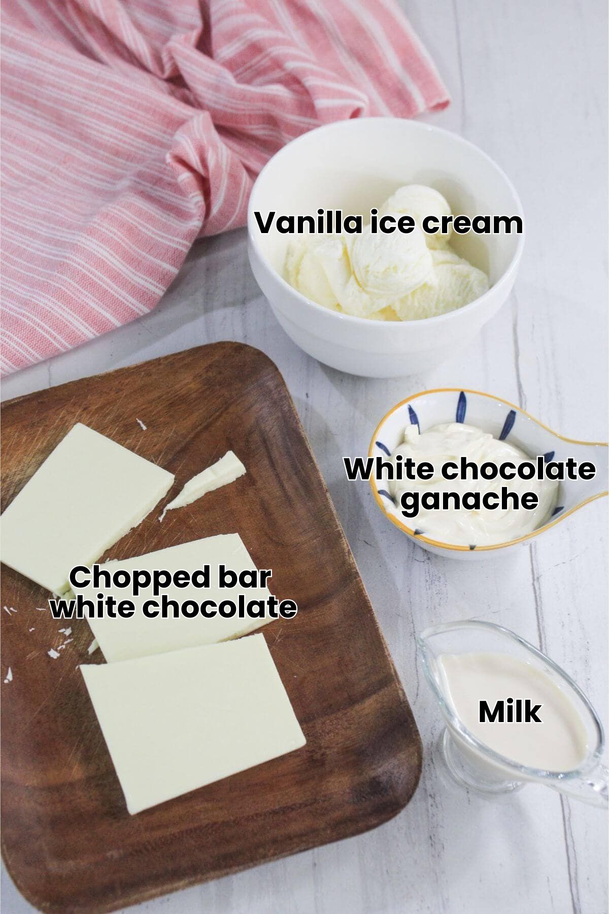 A wooden board with three blocks of cream cheese, a bowl of sliced butter, a small dish of mayonnaise, and a glass jug of cream on a white surface with a pink striped cloth.