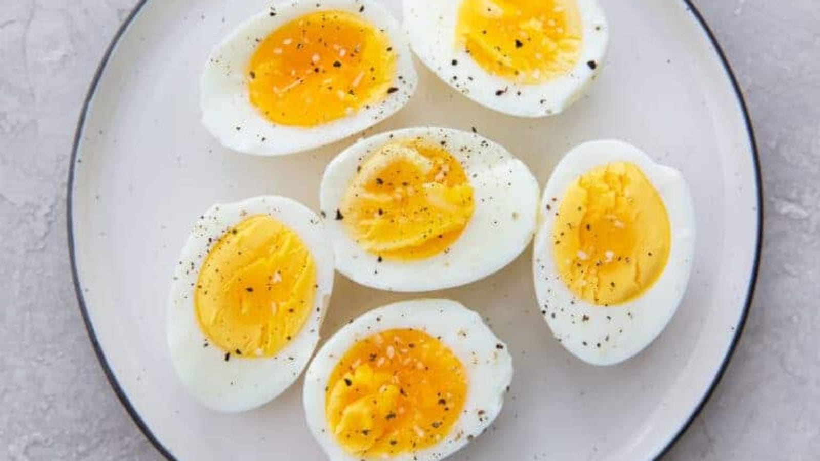 Pefected Air Frer Boiled Eggs with sallt and pepper on a white plate.