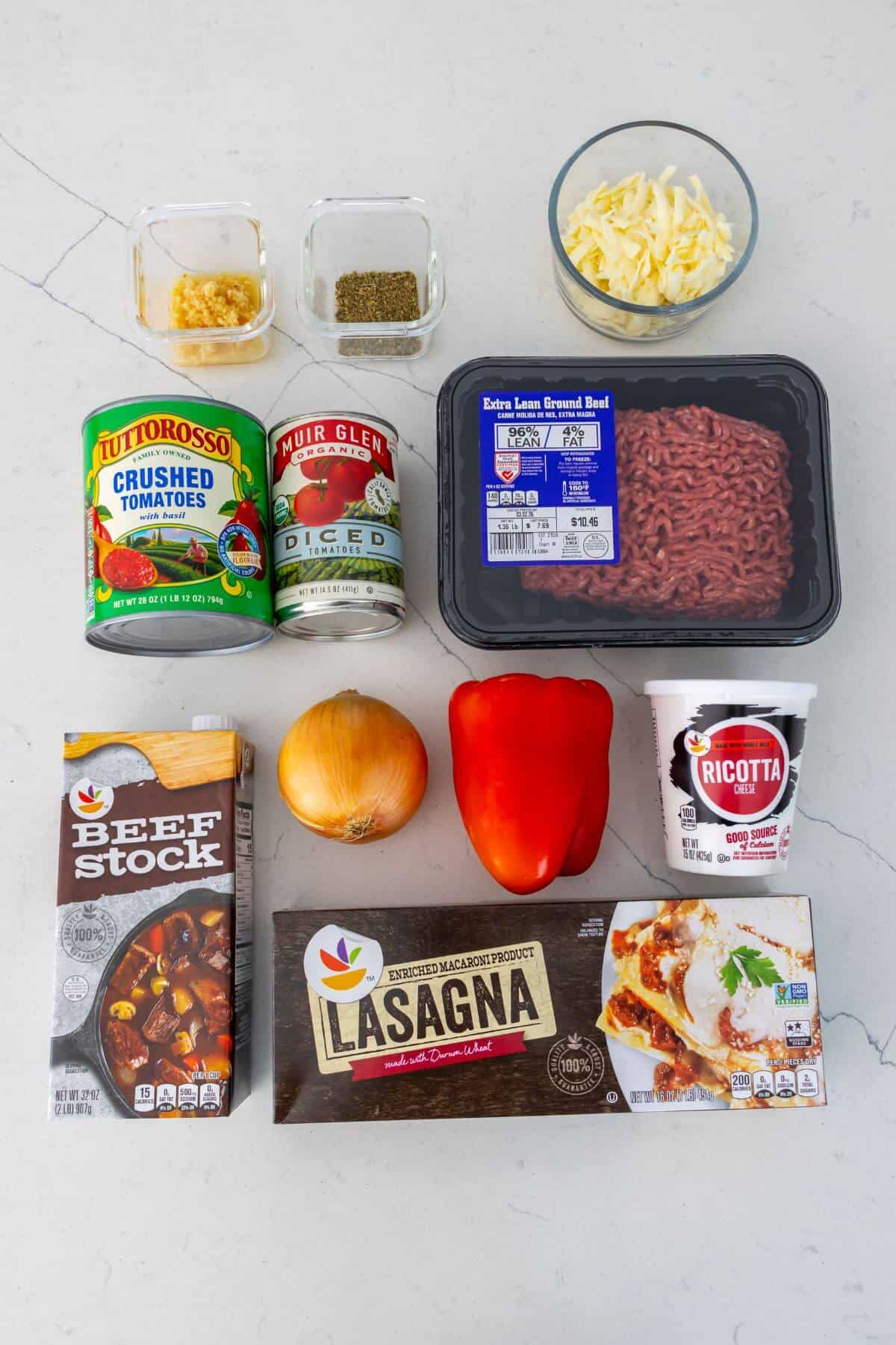 Ingredients for lasagna including lasagna noodles, ground beef, ricotta, mozzarella, onion, red bell pepper, beef stock, tomatoes, crushed tomatoes, garlic, oregano, and basil.