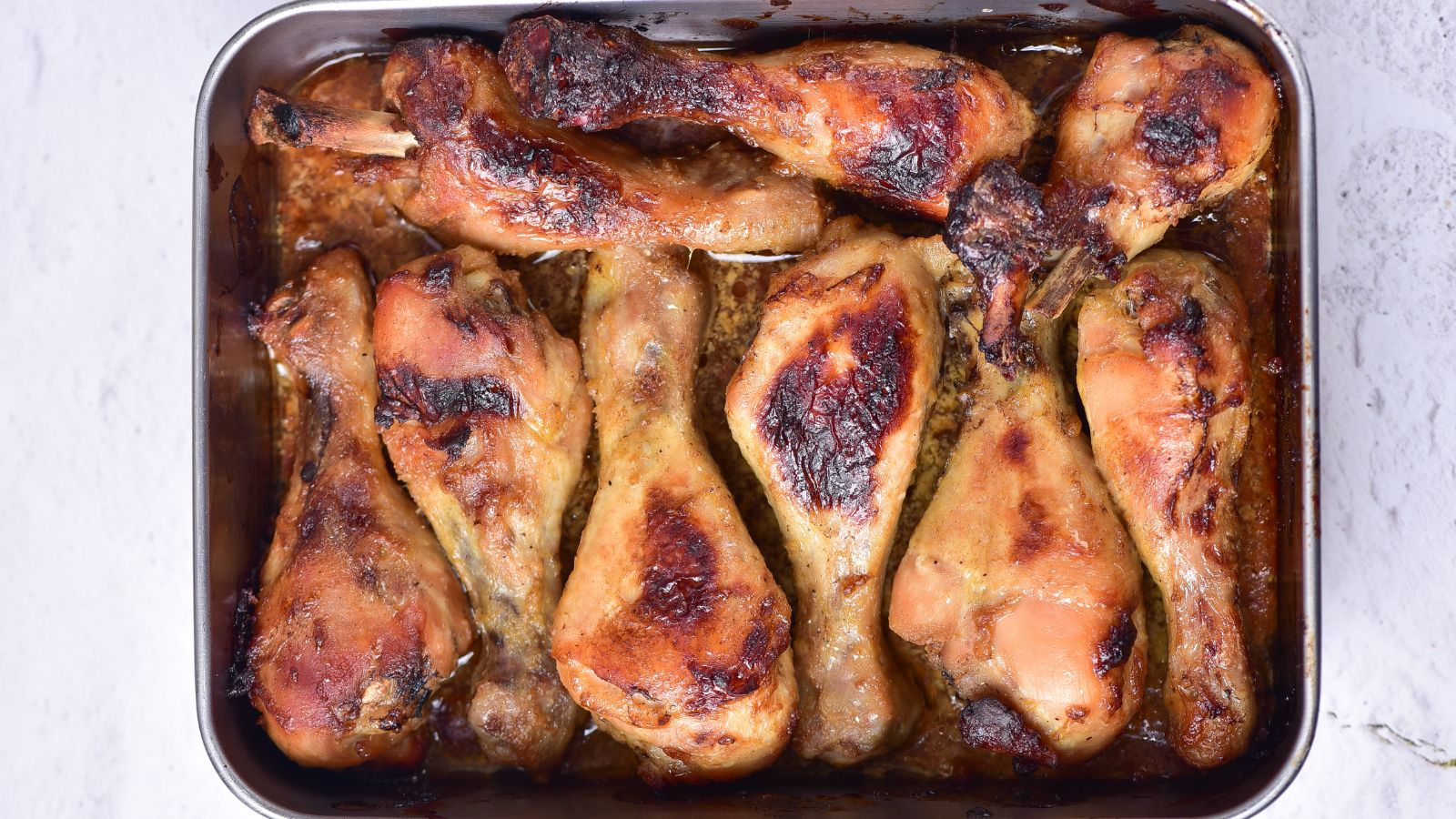 Honey mustard chicken drumsticks cooked in a baking pan.
