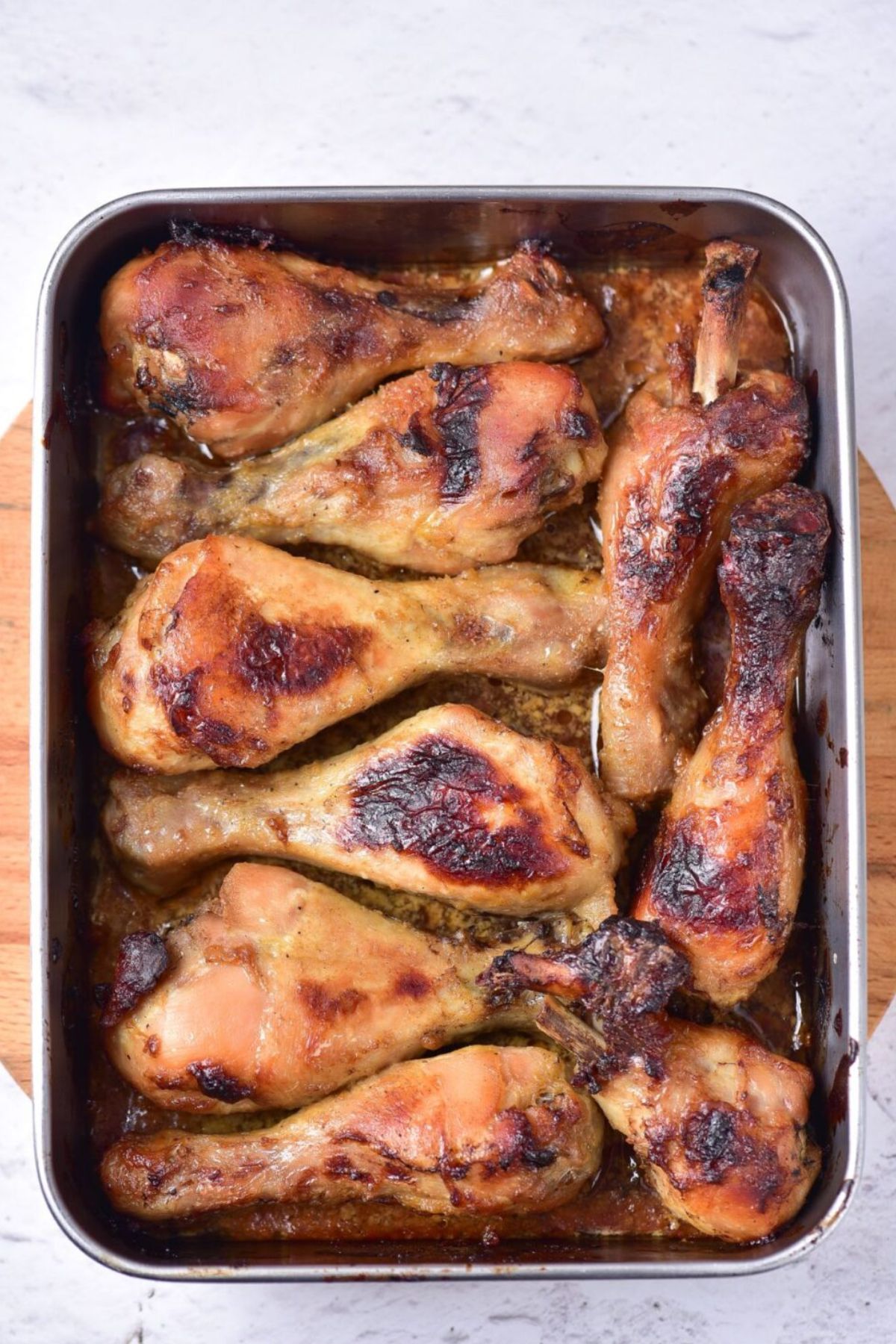 Honey mustard chicken drumsticks cooked in a baking pan.