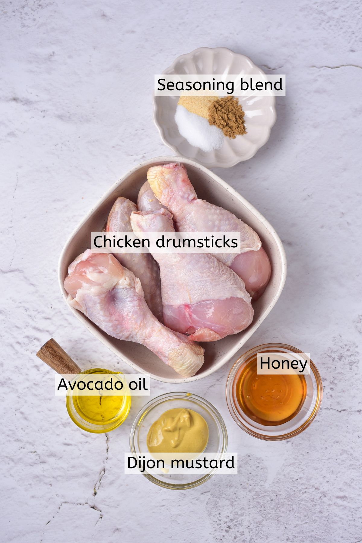 Ingredients to make chicken drumsticks in measuring cups with text labels over top.