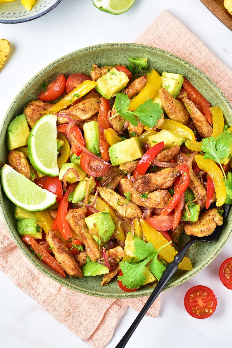 Chicken fajita salad with bell peppers and avocados in a bowl.