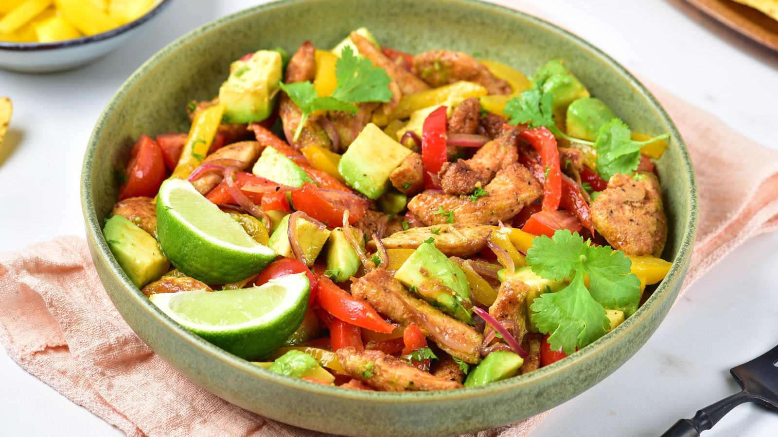 Chicken fajita salad with bell peppers and avocados in a bowl.
