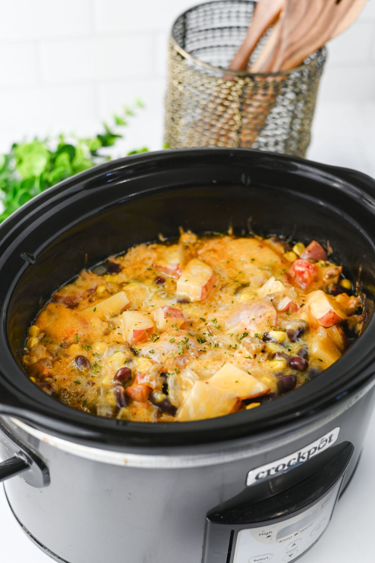 Slow cooker with cowboy casserole topped with cheese in it.