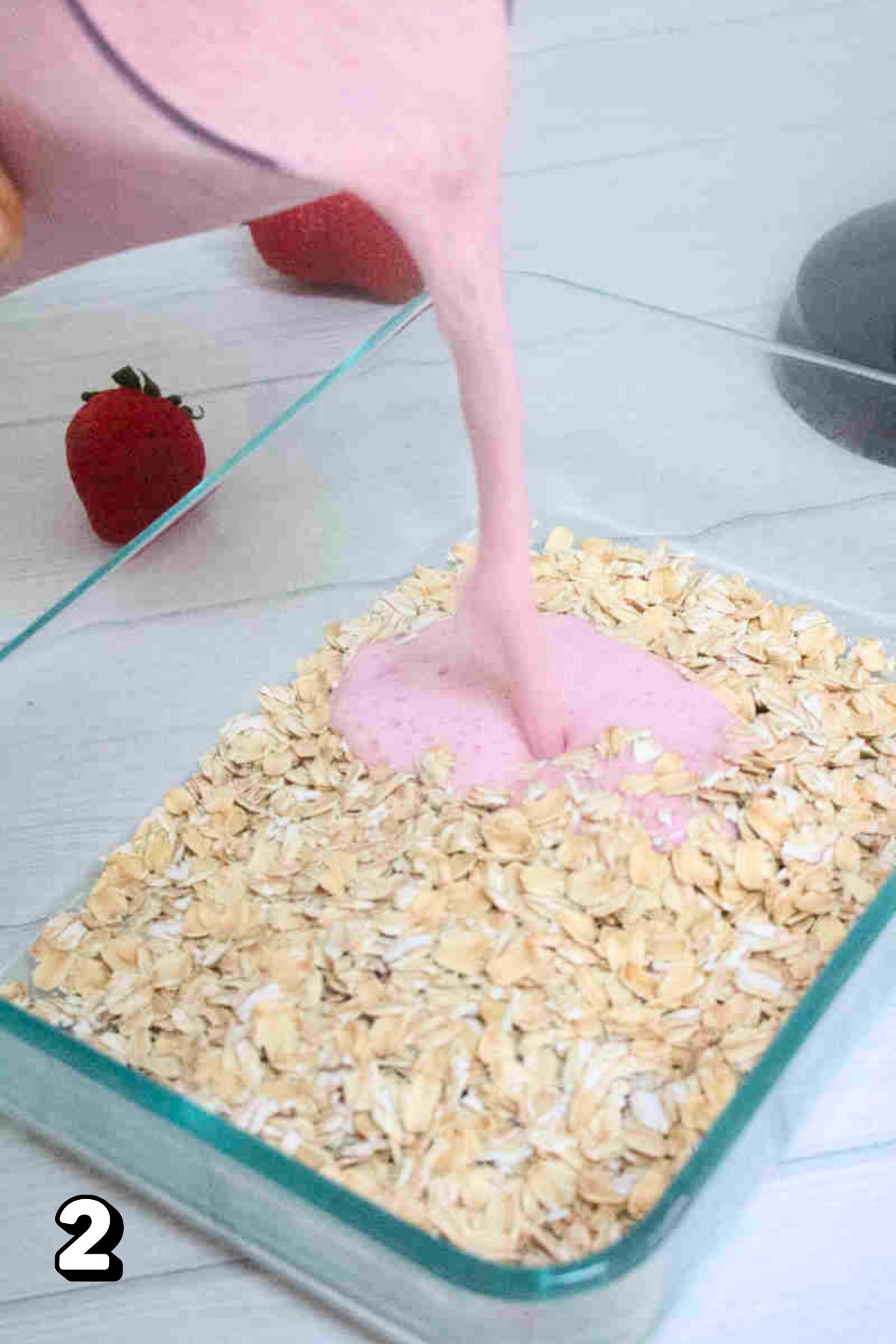 Blended berries, yogurt, and milk being poured into a container with oats.