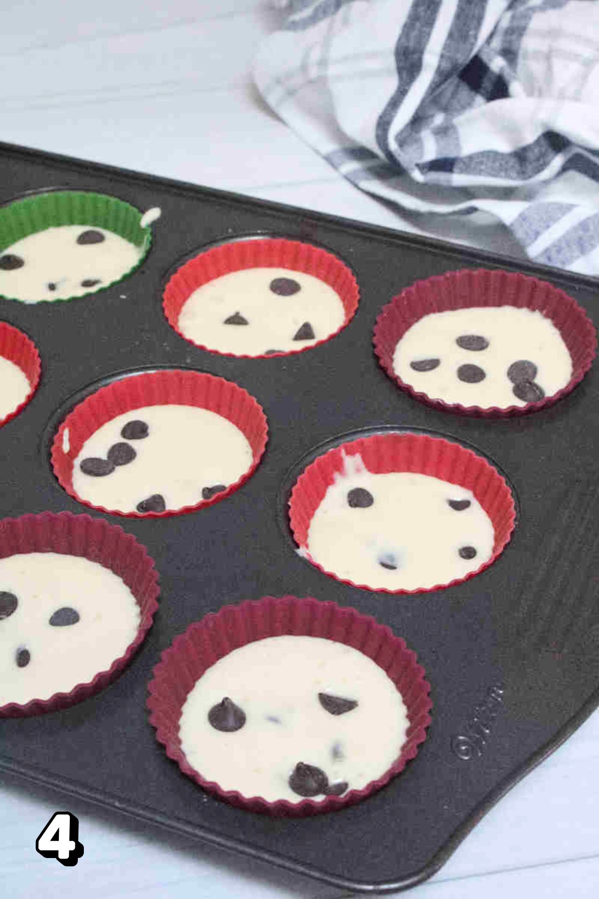 Raw yogurt muffin batter in liners topped with chocolate chips.