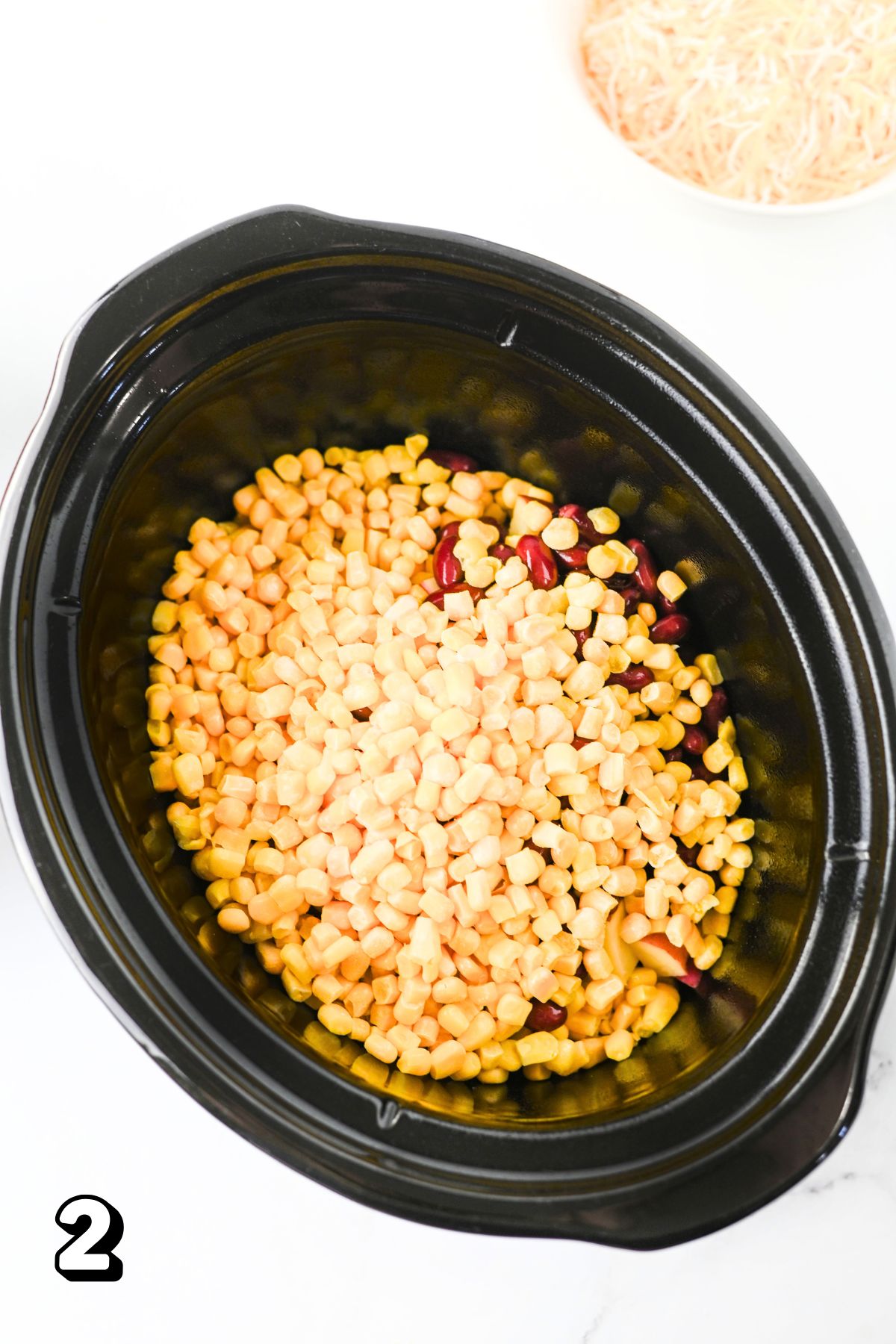 Slow cooker with frozen corn and kidney beans in it.