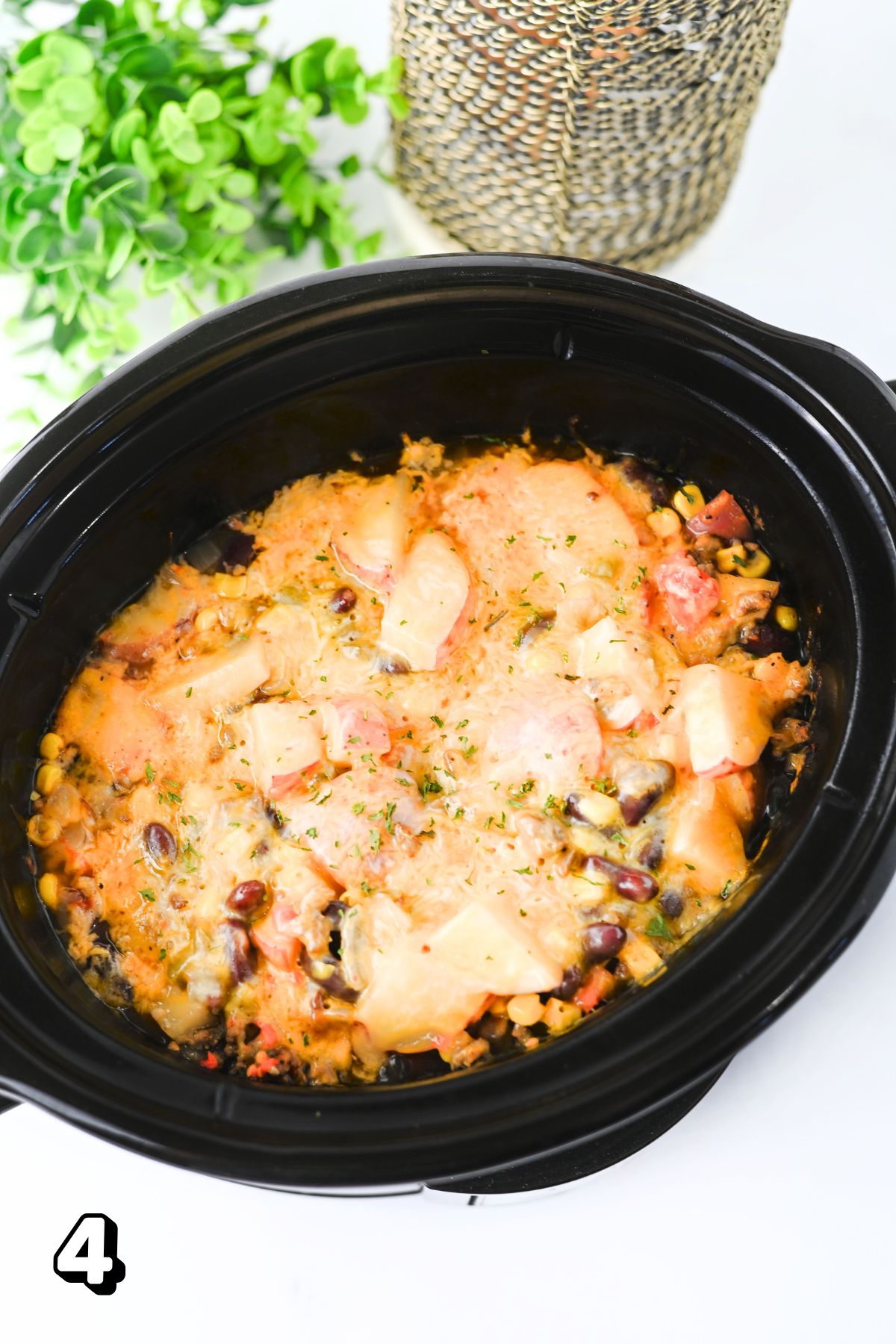 Slow cooker with cowboy casserole topped with cheese in it.