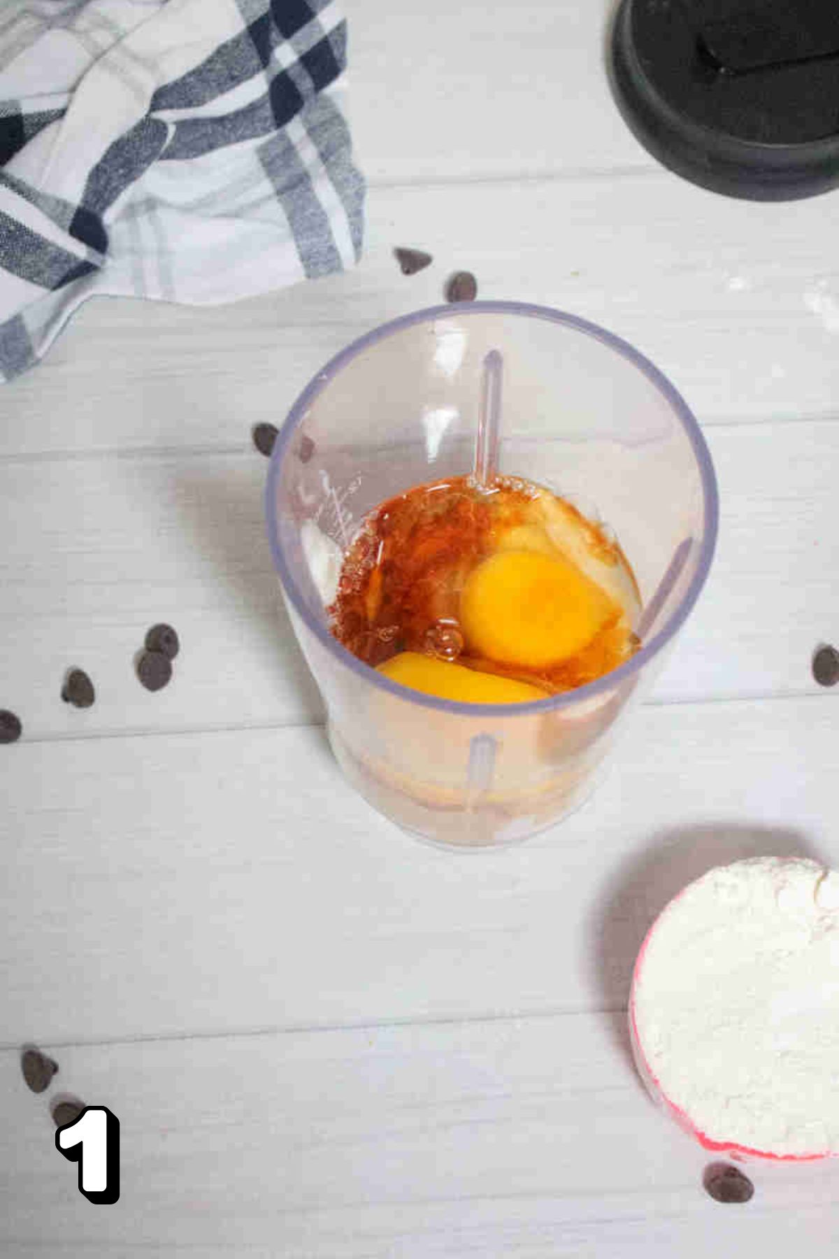 A blender with raw eggs and vanilla in it.