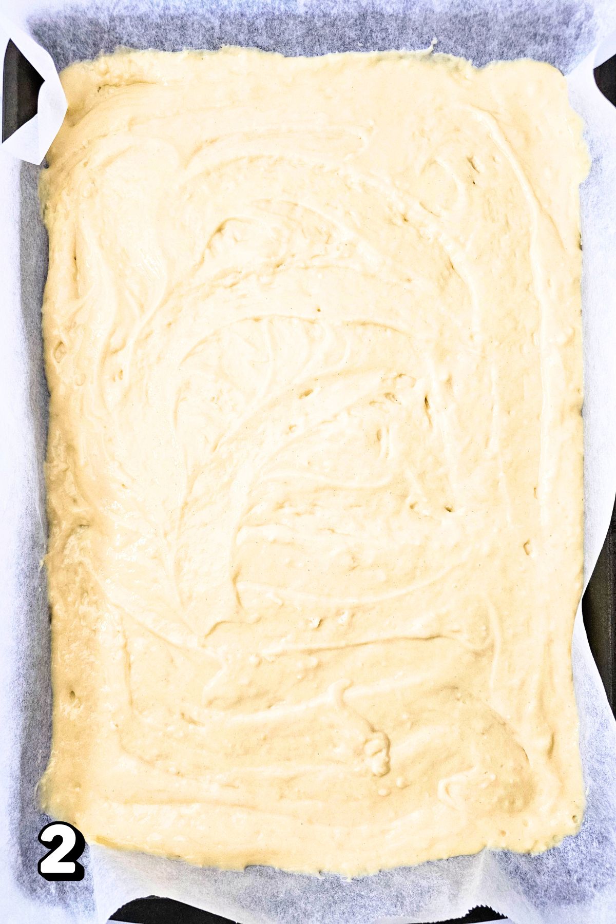 Raw pancake batter on a lined baking sheet.