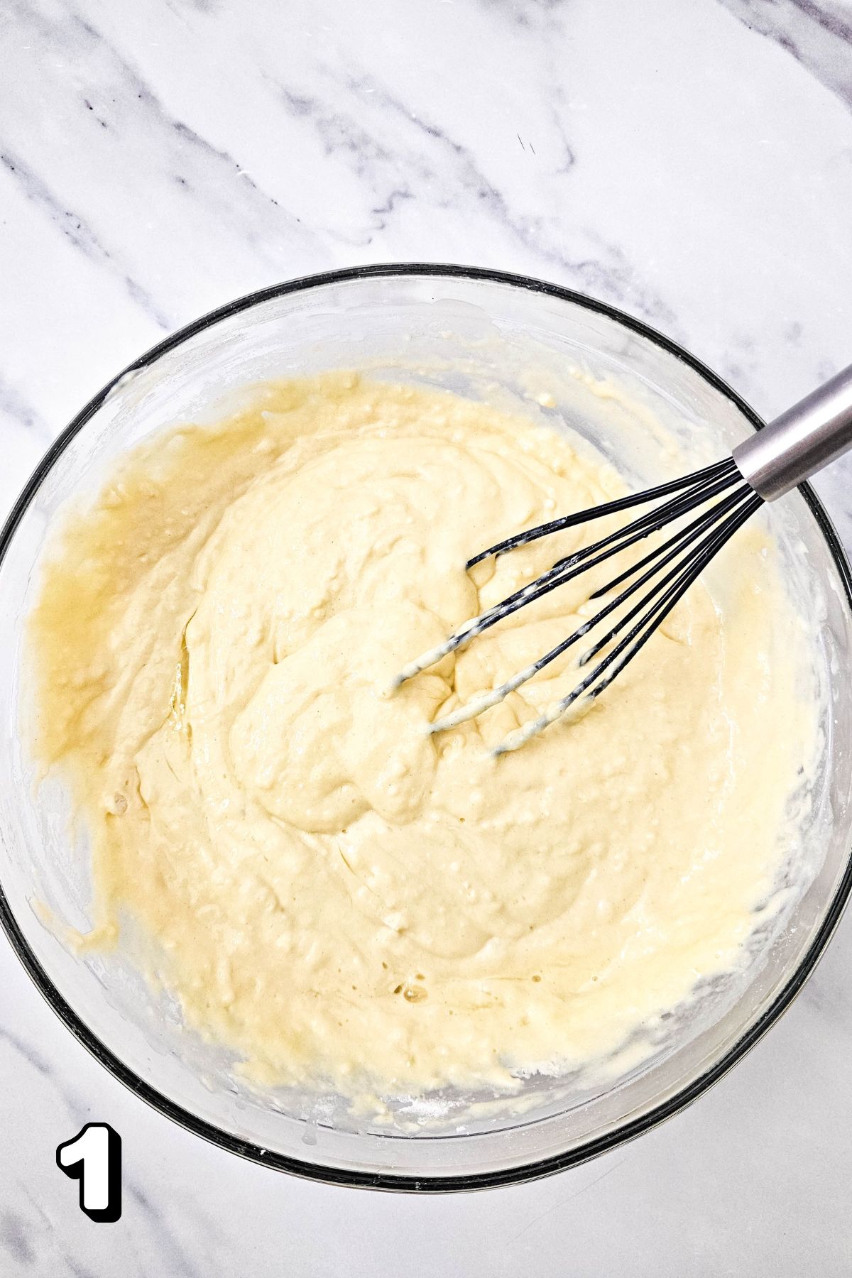 Pancake batter being mixed in a glass bowl.