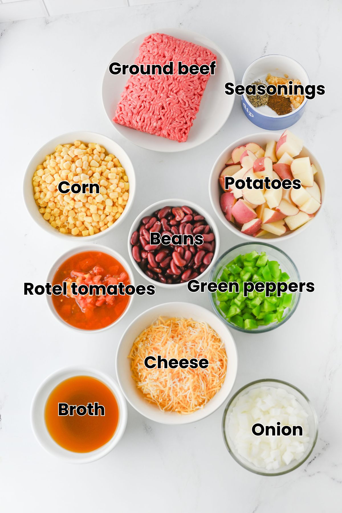 Multiple ingredients like green peppers, beans, cheese, and beef in bowls with text on them.