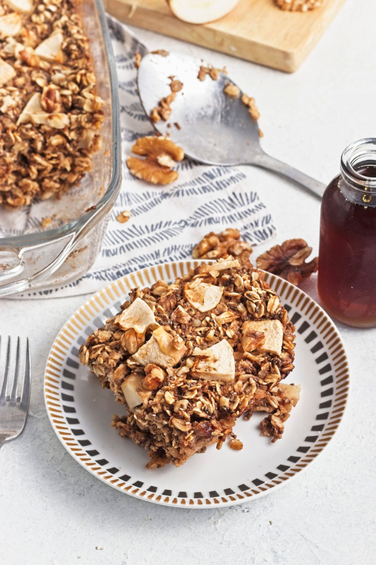 White plate with apple baked oatmeal on top and a baking dish behind it.
