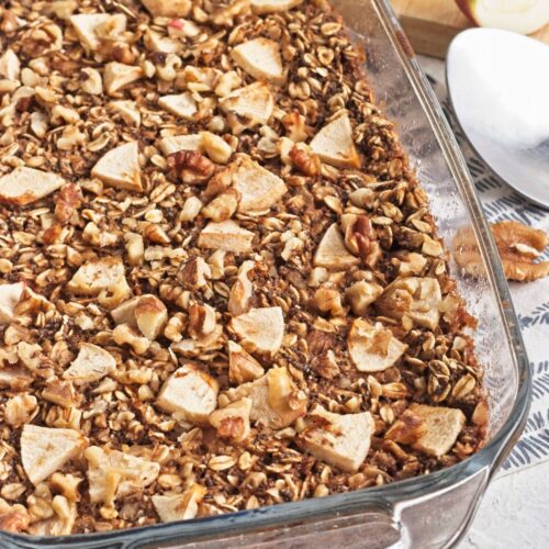 Baked apple oatmeal topped with apples in a glass baking dish.