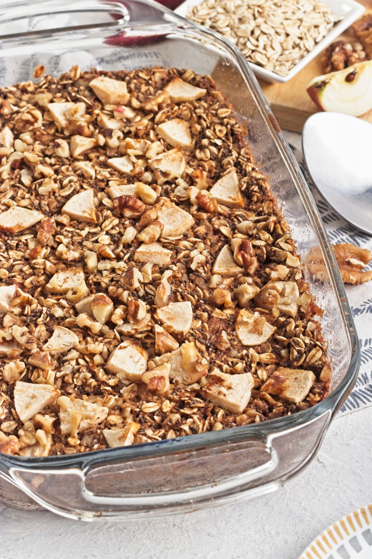 Baked apple oatmeal topped with apples in a glass baking dish.