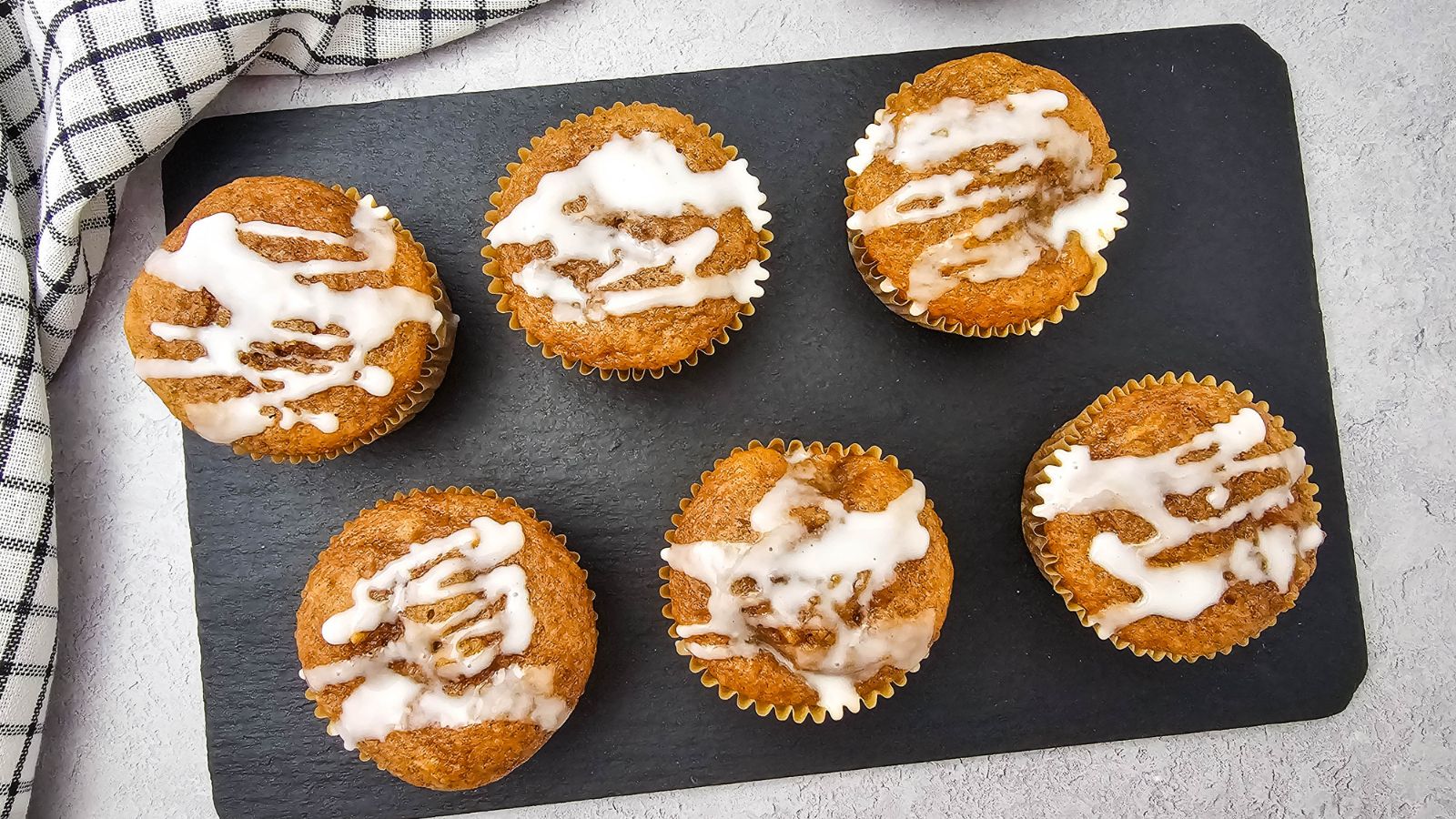 Apple pie muffins with cake mix lined up on a black cutting board.