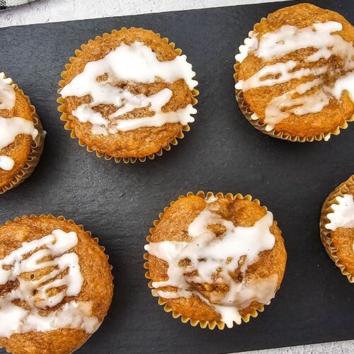 Apple pie muffins with cake mix lined up on a black cutting board.