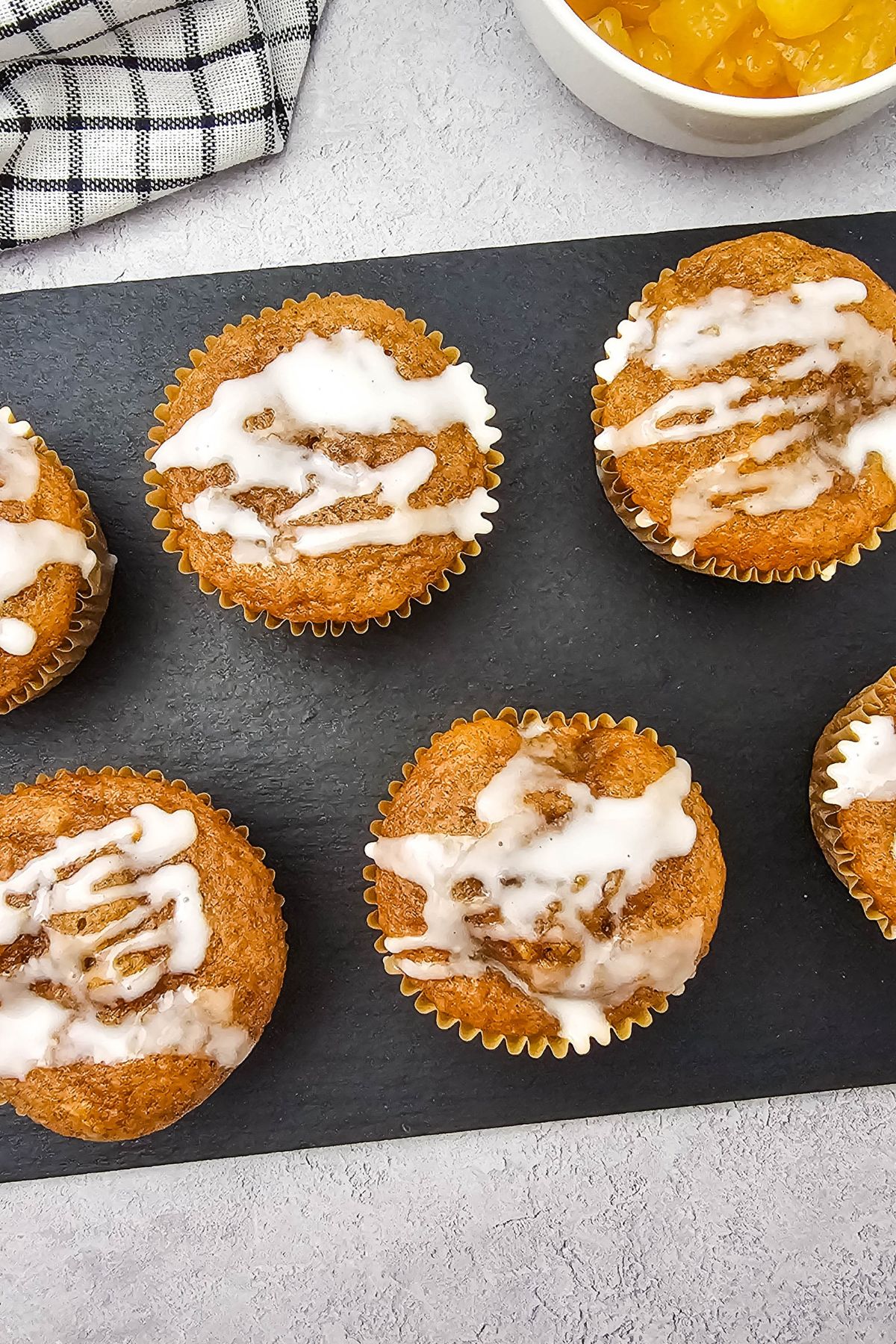 Apple pie muffins with cake mix lined up on a black cutting board.