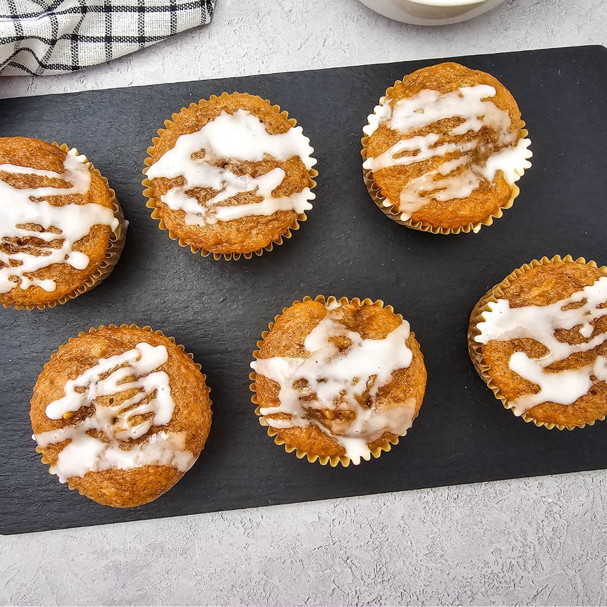 Apple pie muffins with cake mix lined up on a black cutting board.