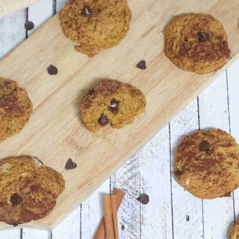 Pumpkin chocolate chip cookies on a cutting board and around them.