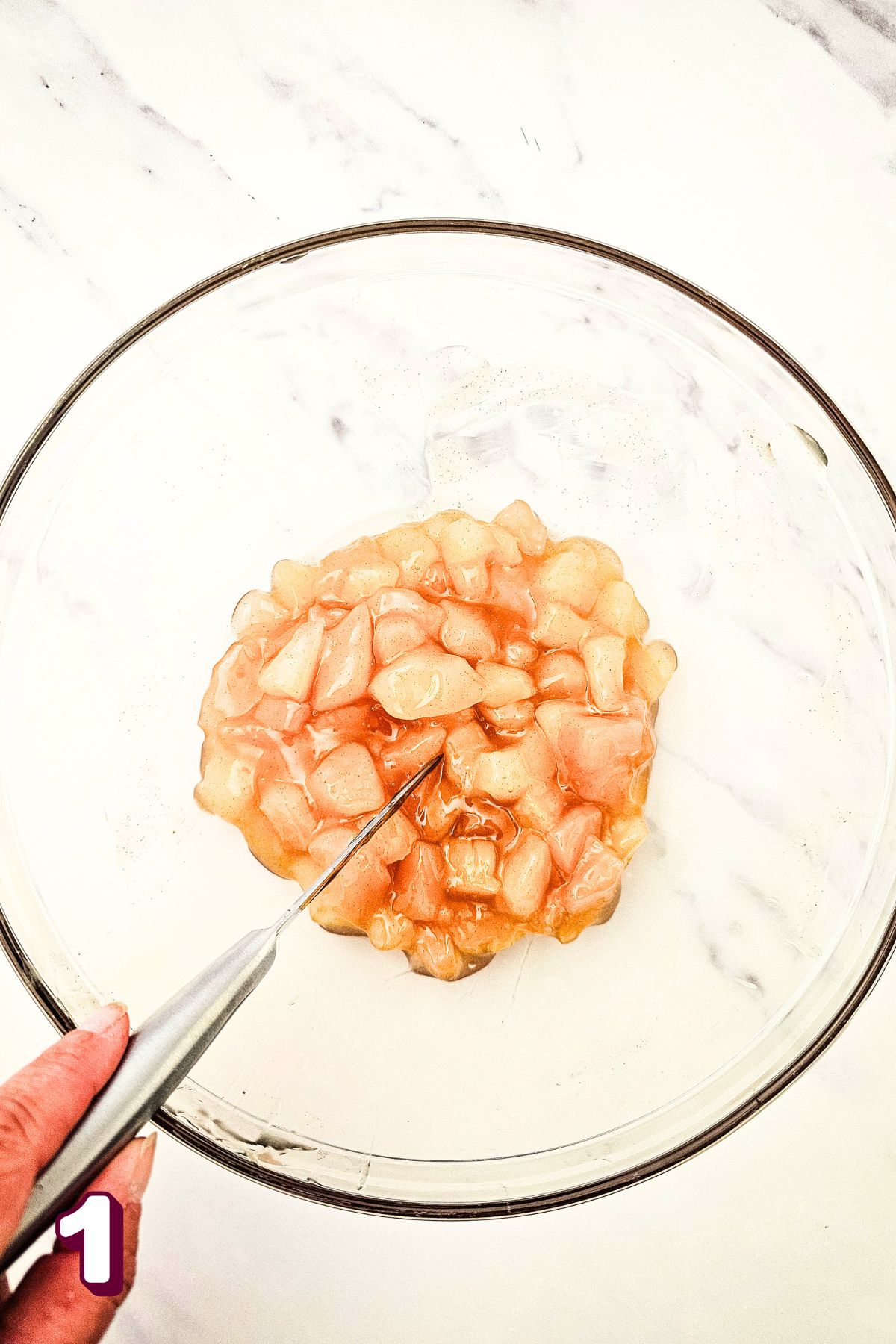Canned apples in a bowl being cut with a knife.